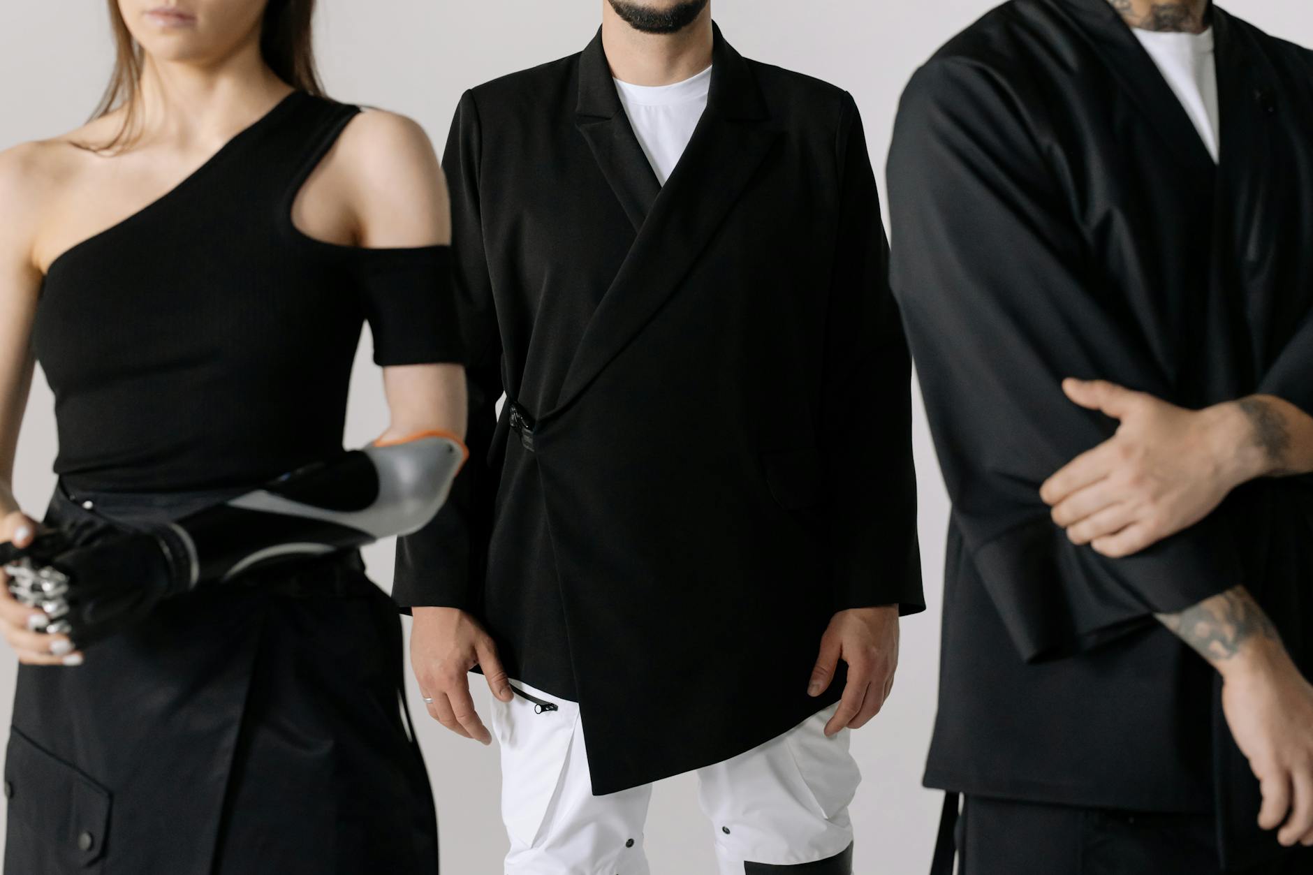 Fashionable group showcasing a prosthetic arm with modern black clothing indoors.