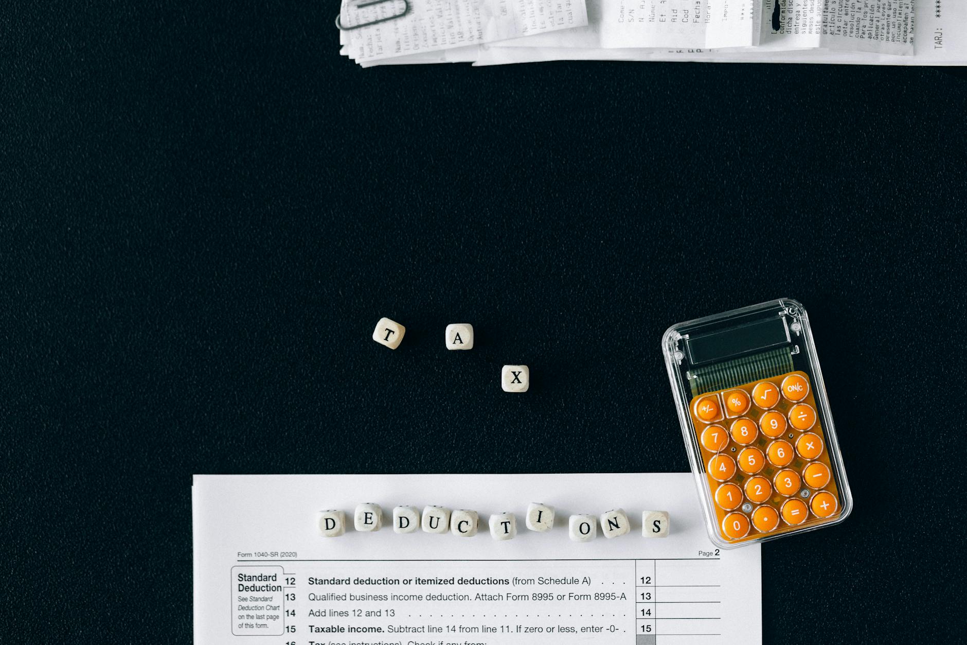 Top-down view of tax deduction items on a black background with a calculator and forms, emphasizing financial planning.
