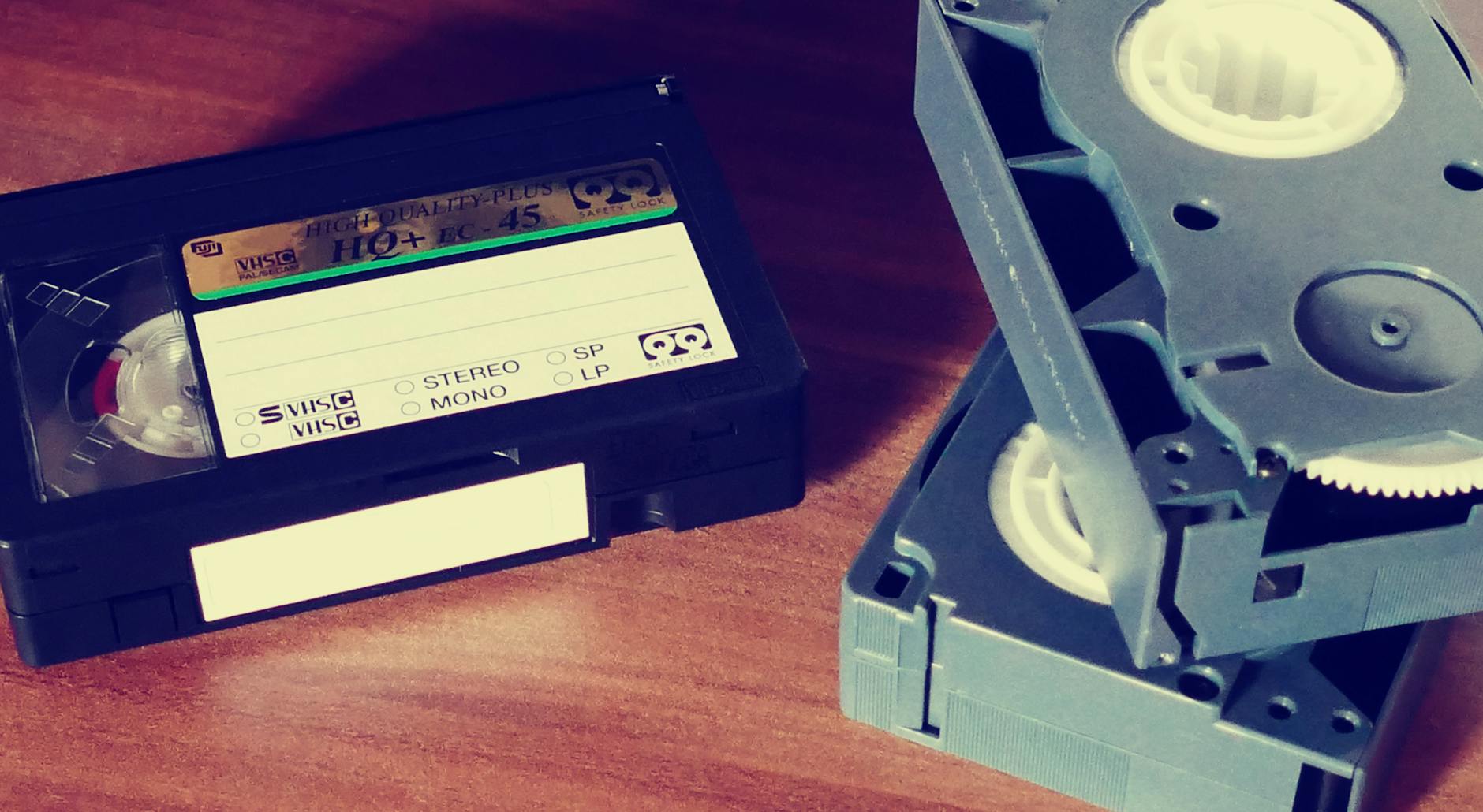 Close-up of vintage VHS tapes on a wooden table, highlighting old technology and nostalgia.