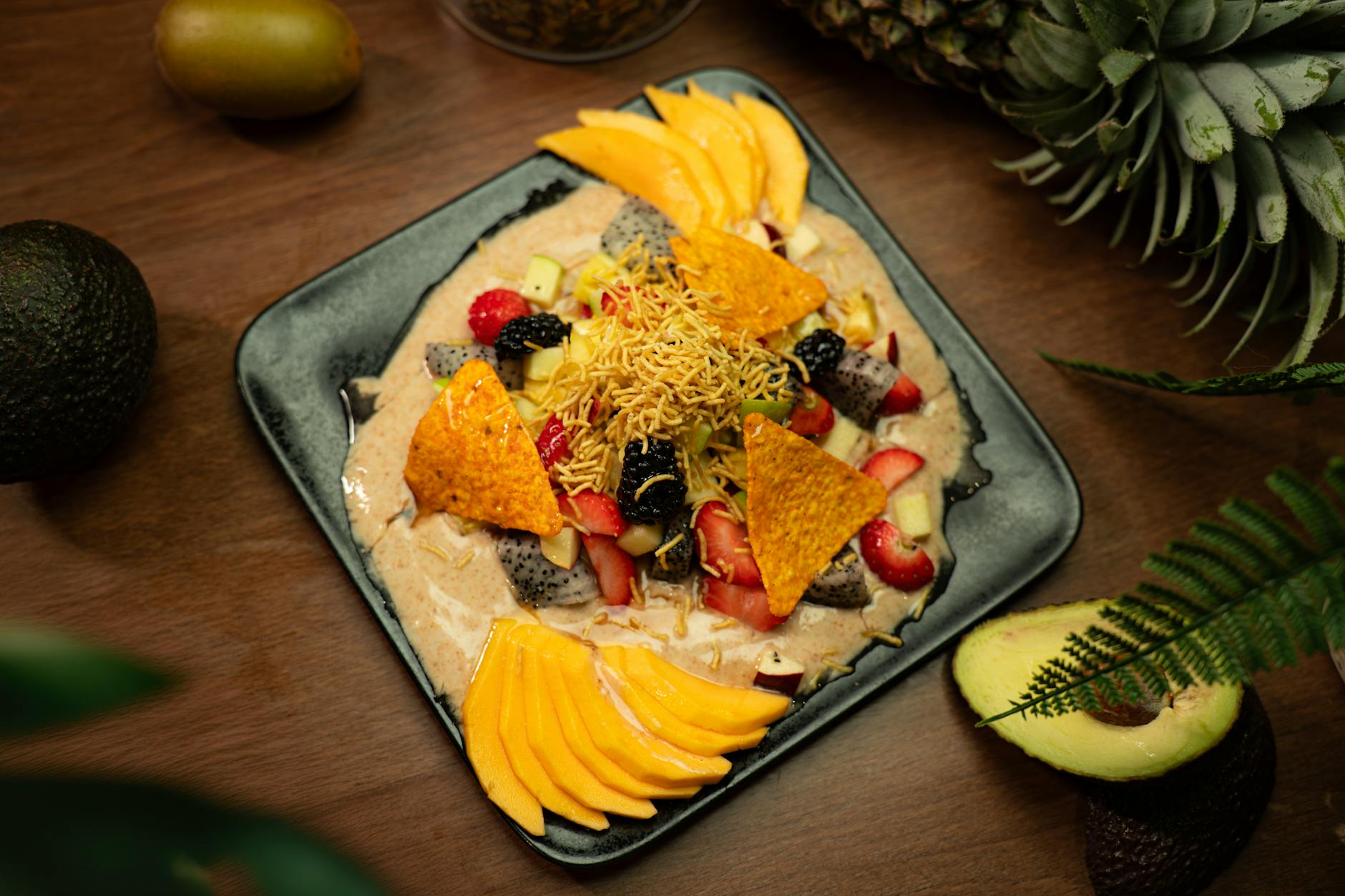 Vibrant fruit salad with mango, berries, and nachos on a sleek platter.