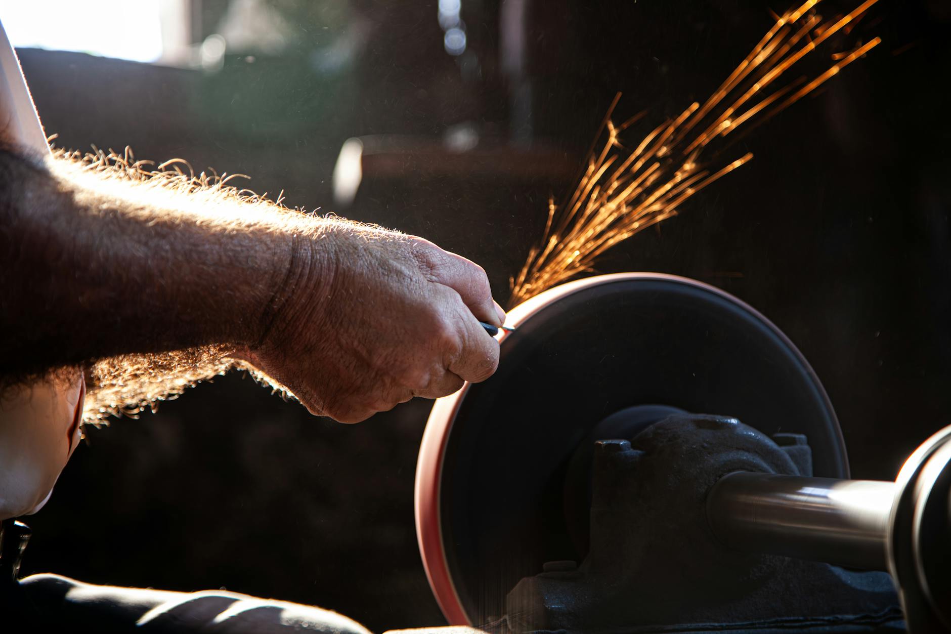 An artisan sharpens a blade on a grinder, creating bright sparks in Yatağan, Türkiye.