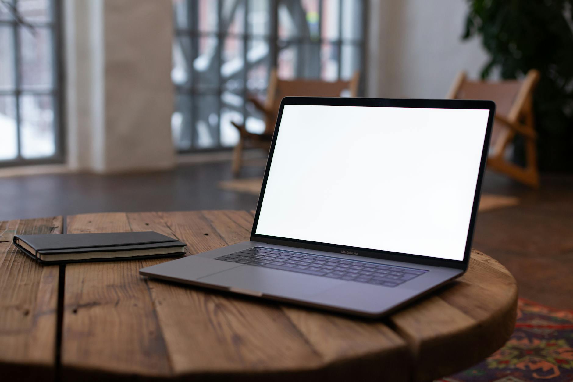A sleek laptop on a wooden table with an open blank screen, perfect for mockup use in modern interiors.