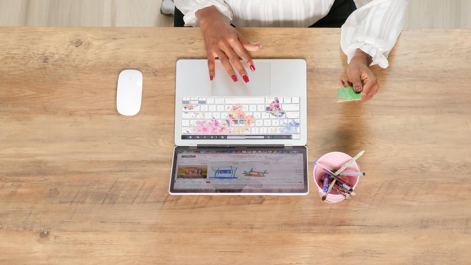 Female hand using a credit card while shopping online on a laptop from a top view angle.