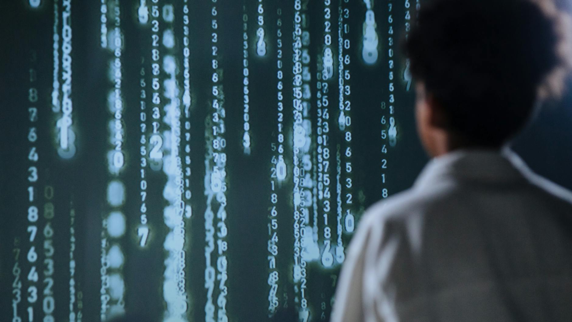 An individual viewing glowing numbers on a screen, symbolizing technology and data.