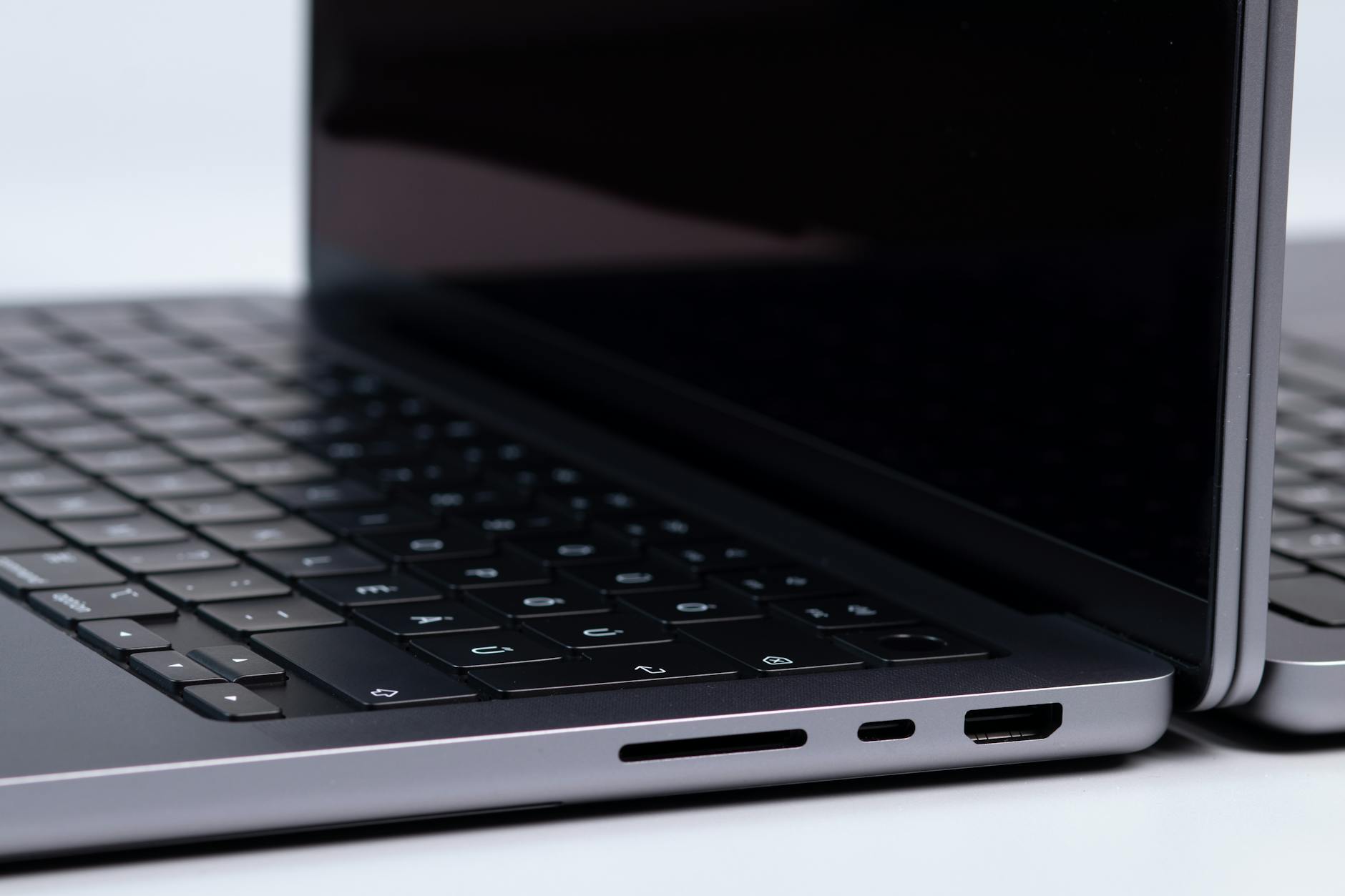 Detailed view of laptop ports and keyboards on a white surface, showcasing modern technology.