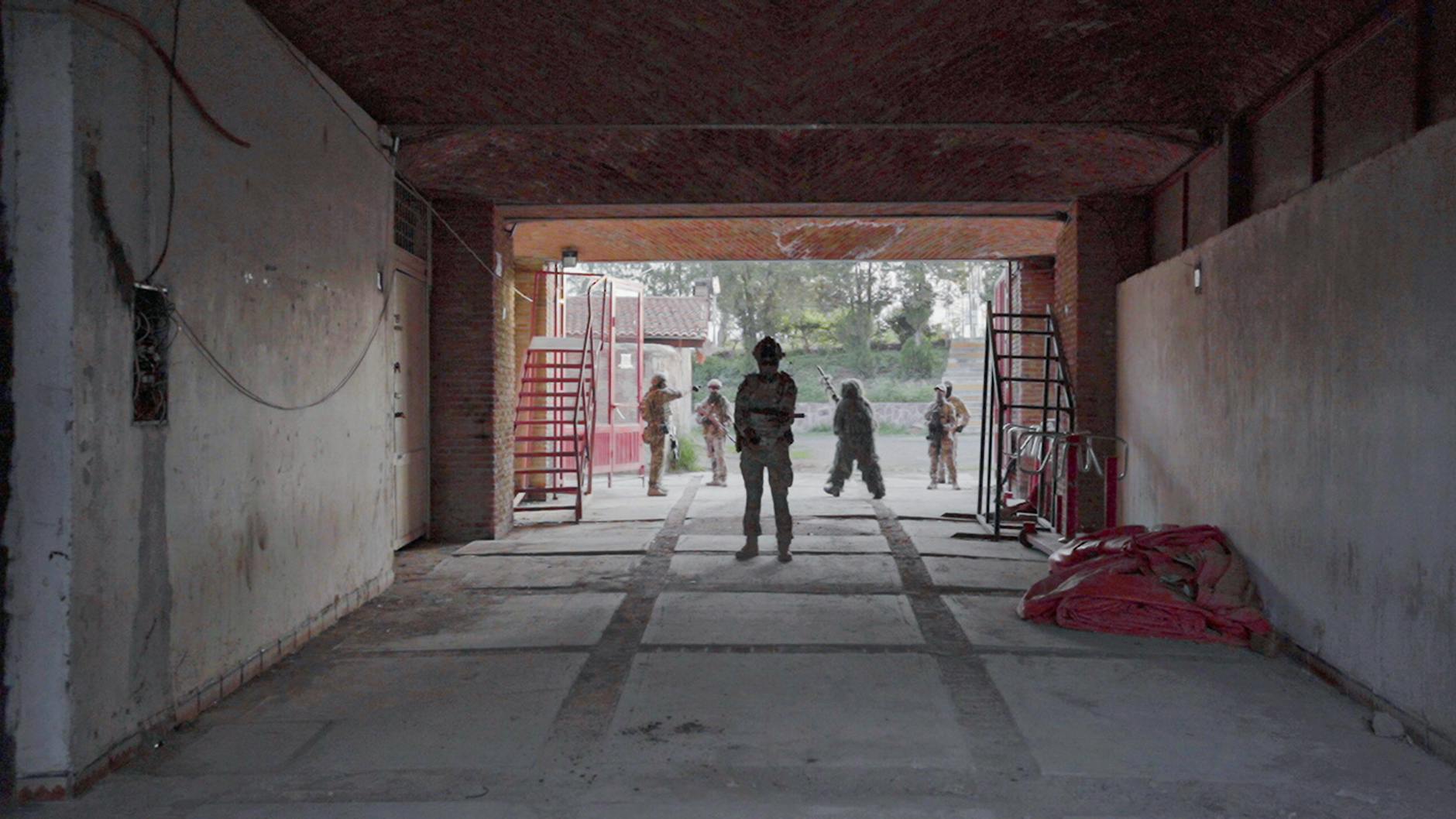 Soldiers wearing camouflage uniforms in a garage setting, ready for action.