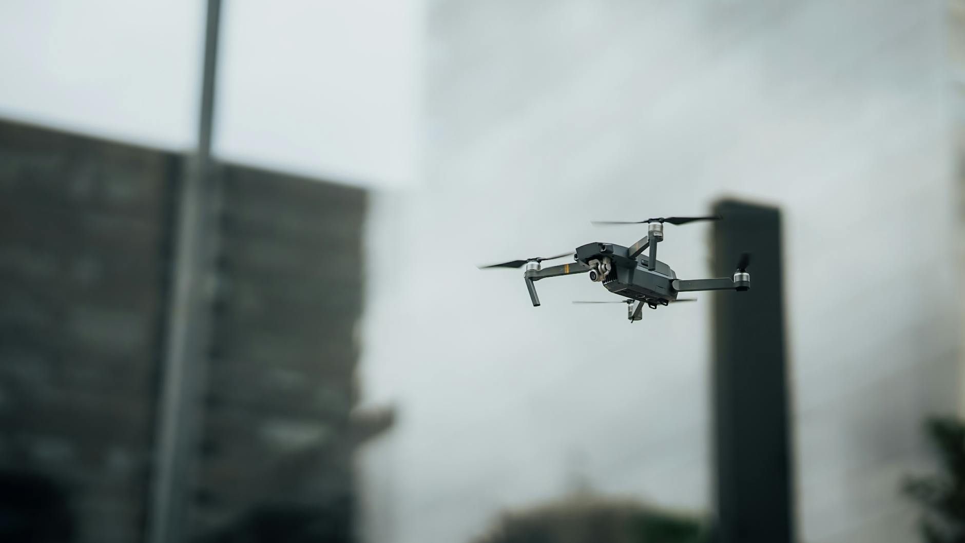 Close-up of a drone flying amidst city skyscrapers, showcasing modern technology.