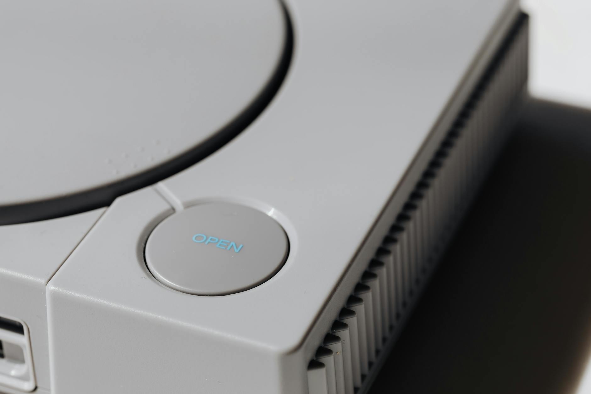 Detailed shot of a classic Sony PlayStation, highlighting the iconic open button and retro design.