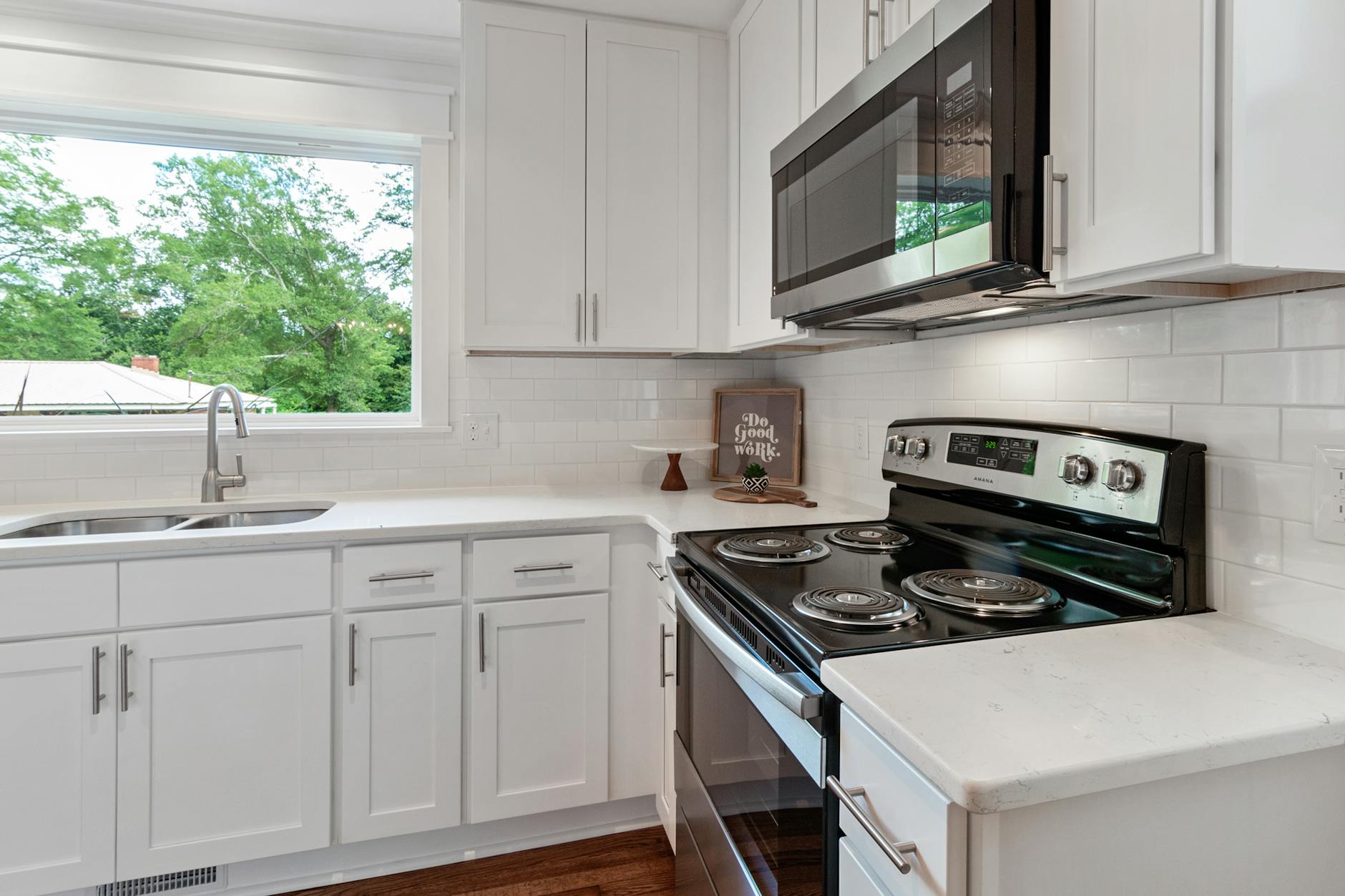 Bright modern kitchen with white cabinetry and stainless steel appliances.