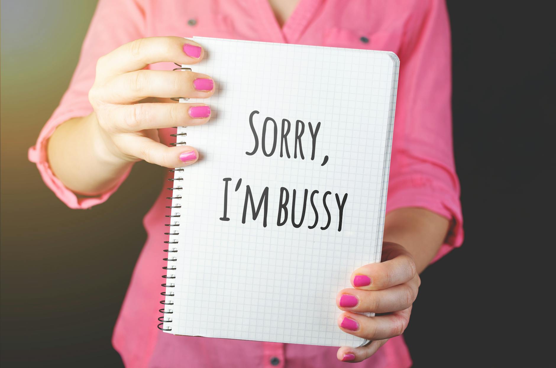Woman holding a notebook with a handwritten message featuring a spelling error, showcasing humor and communication.
