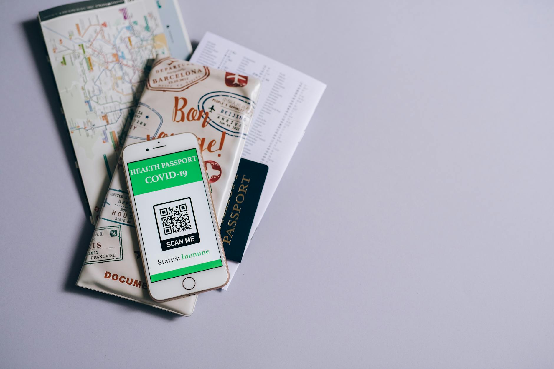 A health passport for COVID-19 displayed on a smartphone alongside travel documents.