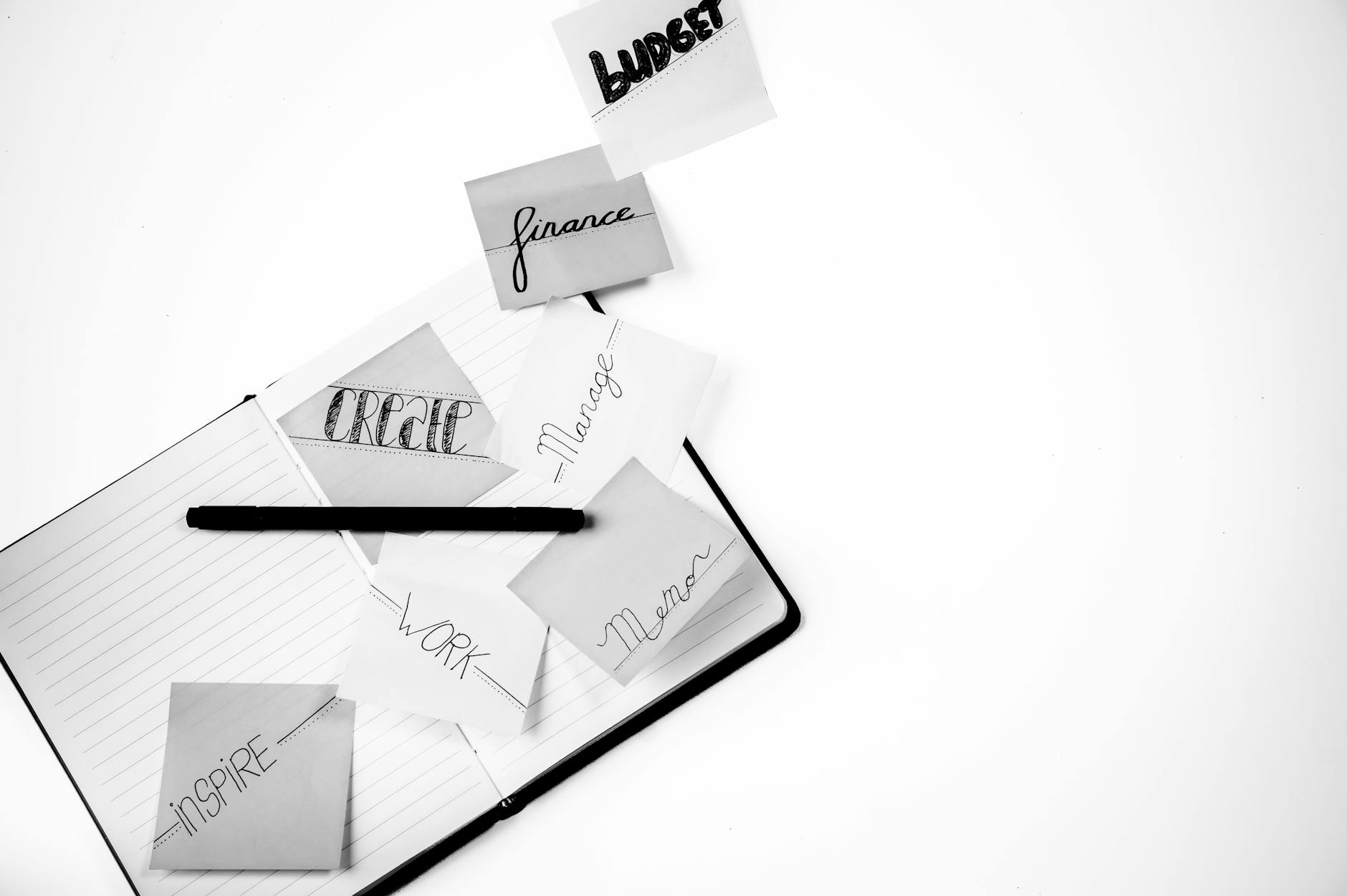 Black and white image featuring a workspace with inspiring handwritten notes and a notebook.